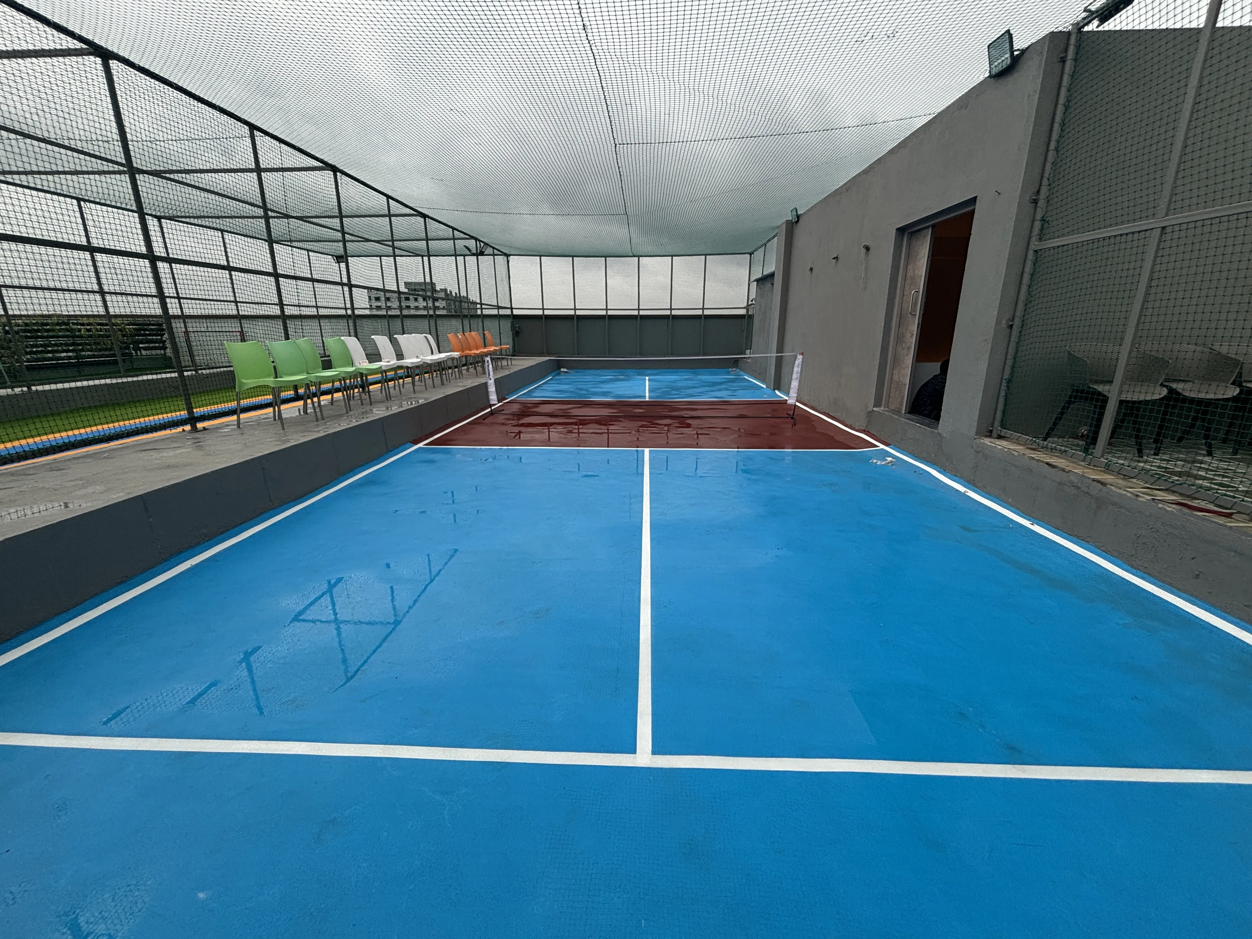 Pickleball paddle hitting a ball mid-air on a blue court with net in background